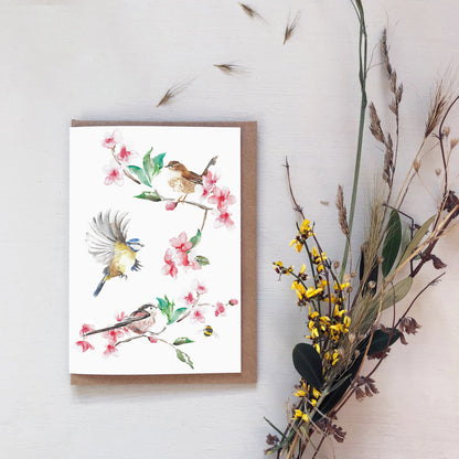 Greeting card with bird s and floral design on a white surface with dried plants.