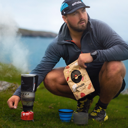 Man outdoors using a camping stove with Exhale products