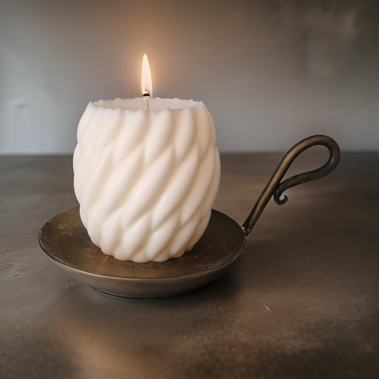 White textured candle on a metal holder 