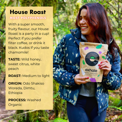 Woman holding an Exhale coffee bag with product details on a natural background