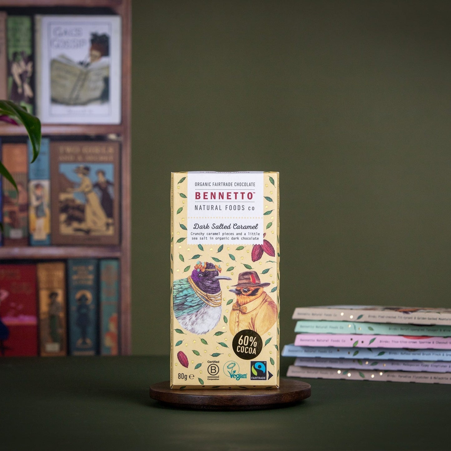 Bennetto chocolate bar packaging on a wooden stand with books and a plant in the background