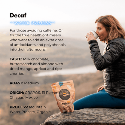 Person drinking from a coffee cup with a coffee package labeled 'exhale' on a mountain background
